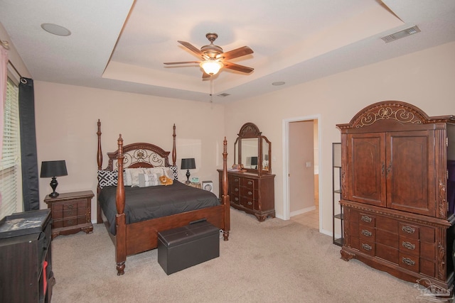 bedroom featuring light carpet, a raised ceiling, and ceiling fan