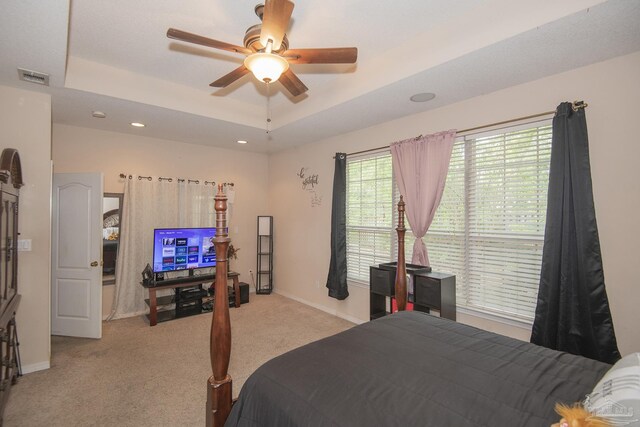 bedroom featuring light carpet, a raised ceiling, and ceiling fan