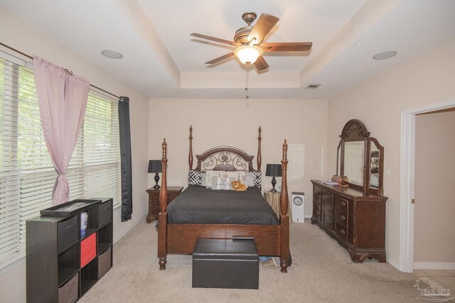 bedroom featuring ceiling fan, light carpet, and a tray ceiling