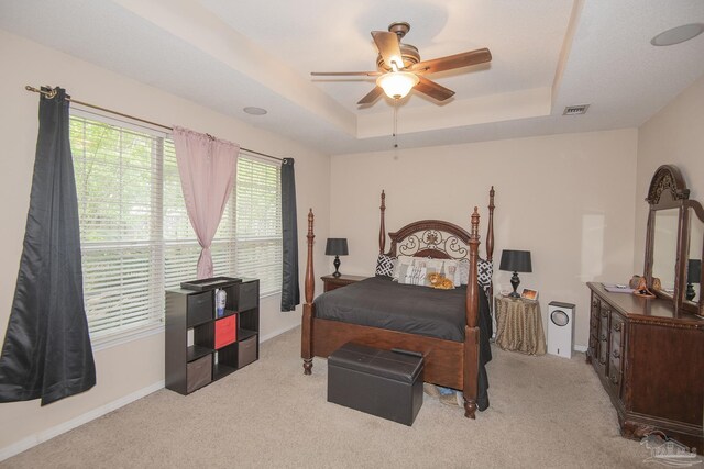 bedroom featuring light carpet, a raised ceiling, and ceiling fan