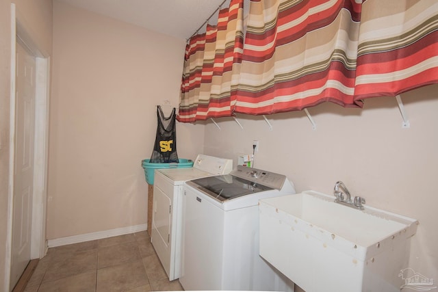 clothes washing area featuring light tile patterned floors, washer and clothes dryer, and sink