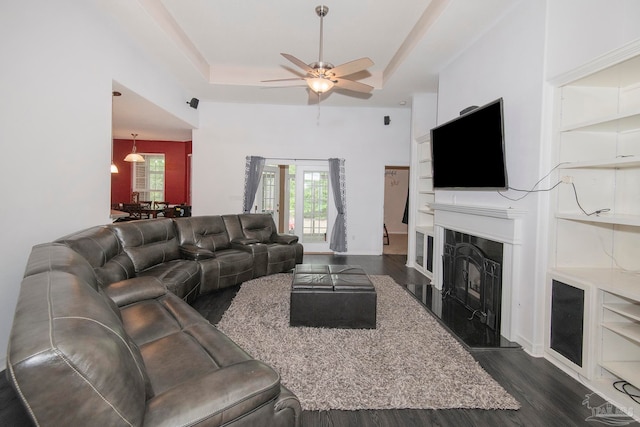 living room with a tray ceiling, ceiling fan, and dark hardwood / wood-style floors