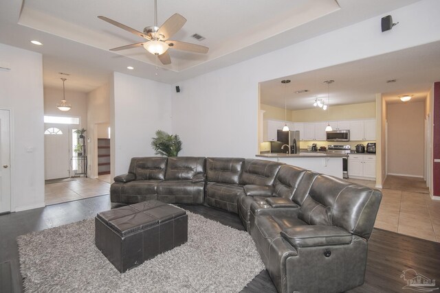 living room featuring ceiling fan, a raised ceiling, dark hardwood / wood-style flooring, and french doors