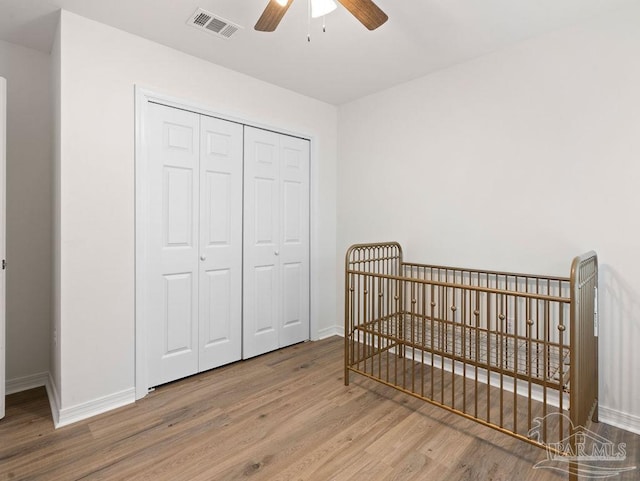 bedroom with hardwood / wood-style floors, a closet, and ceiling fan