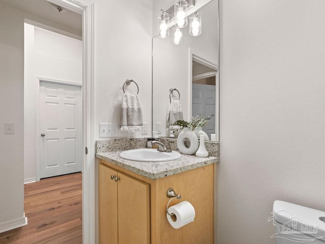 bathroom featuring wood-type flooring, toilet, and vanity