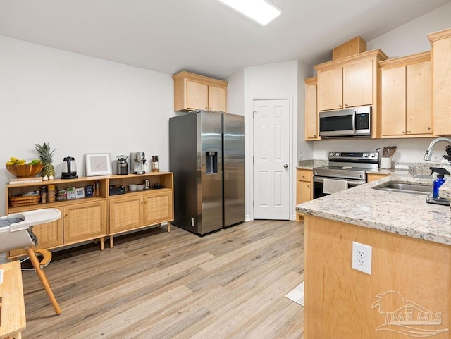 kitchen featuring light brown cabinets, appliances with stainless steel finishes, sink, light wood-type flooring, and light stone countertops