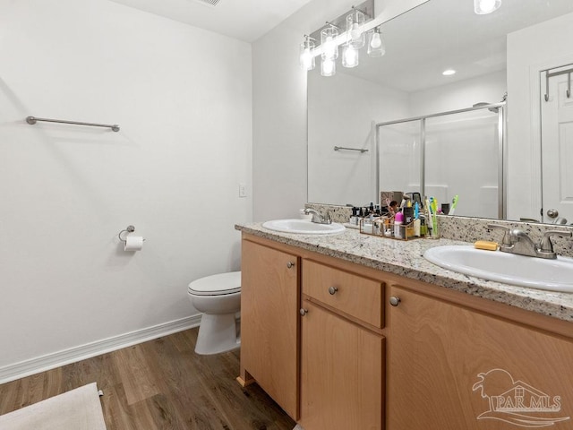 bathroom with hardwood / wood-style floors, toilet, a shower with door, and vanity