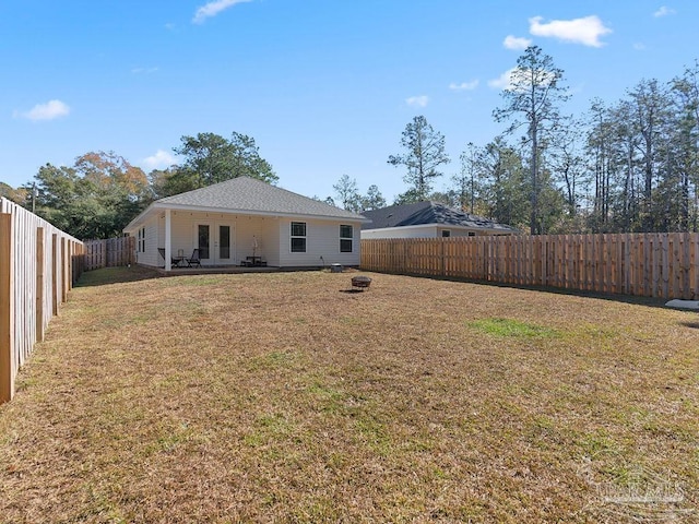 rear view of property featuring an outdoor fire pit and a yard