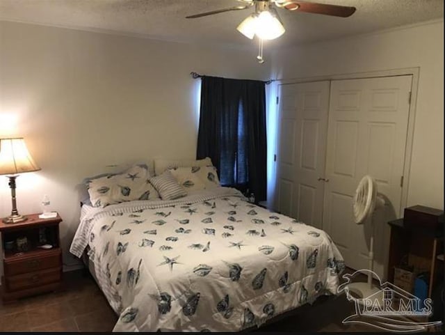 bedroom featuring a closet, a textured ceiling, dark tile patterned floors, and ceiling fan