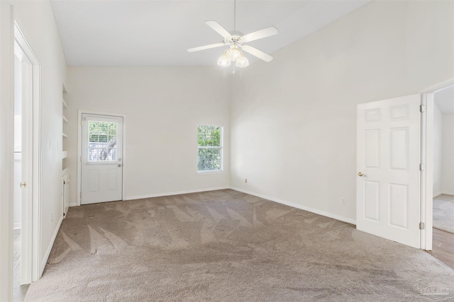 carpeted spare room with ceiling fan and high vaulted ceiling