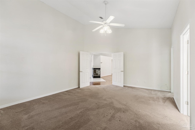 unfurnished bedroom featuring ceiling fan, carpet flooring, a tiled fireplace, and high vaulted ceiling