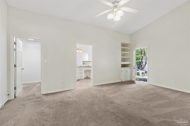 unfurnished bedroom with lofted ceiling, ensuite bathroom, a spacious closet, light carpet, and ceiling fan