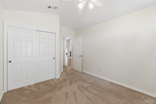 unfurnished bedroom featuring light carpet, vaulted ceiling, a closet, and ceiling fan