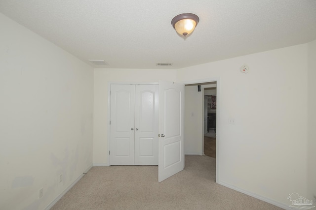 unfurnished bedroom featuring light colored carpet, baseboards, visible vents, and a closet