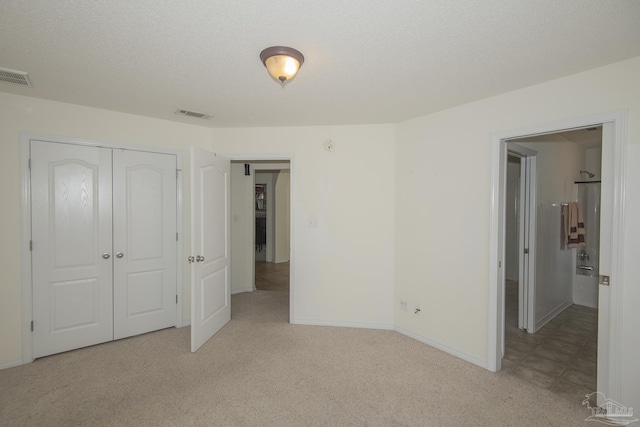 unfurnished bedroom featuring light colored carpet, visible vents, and a closet