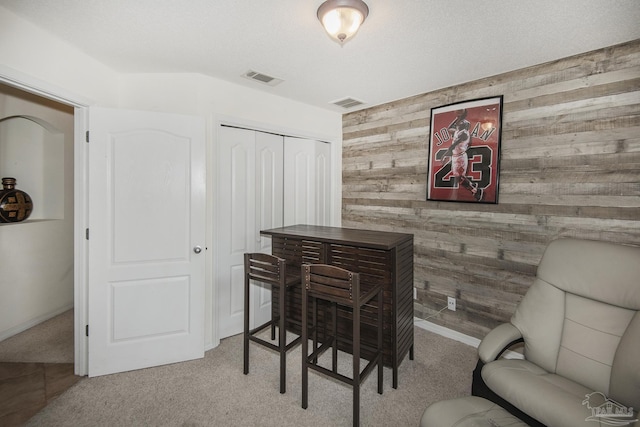 interior space with carpet floors, wood walls, and visible vents