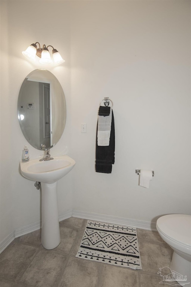 bathroom featuring baseboards, tile patterned floors, and toilet