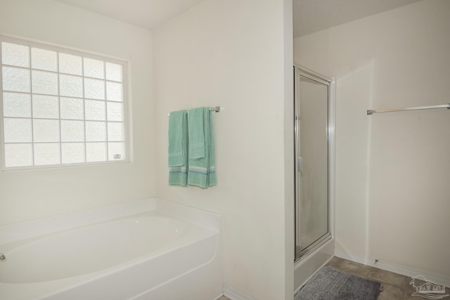 full bath featuring a garden tub, a shower with door, baseboards, and a healthy amount of sunlight