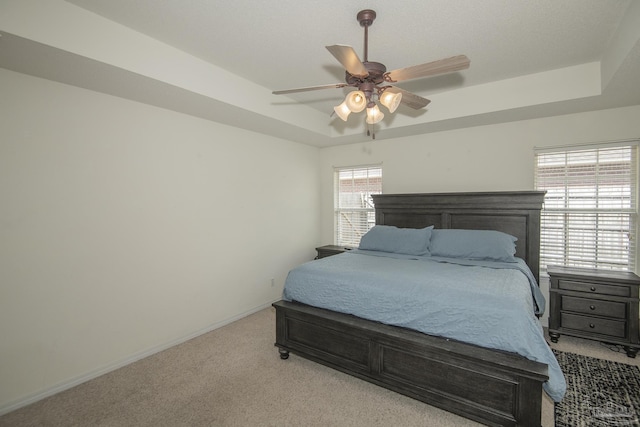 bedroom with carpet flooring, a ceiling fan, a tray ceiling, and baseboards