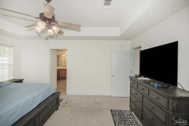 bedroom with light colored carpet, baseboards, visible vents, and a raised ceiling