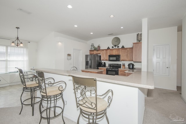 kitchen with brown cabinetry, light countertops, a breakfast bar area, and black appliances