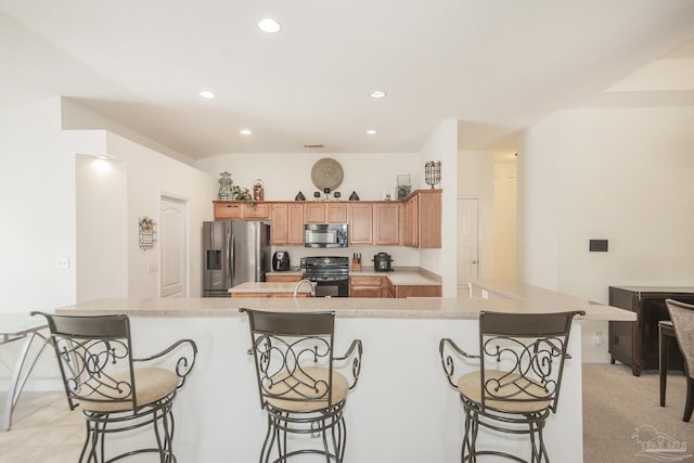 kitchen with recessed lighting, light countertops, black appliances, and a breakfast bar