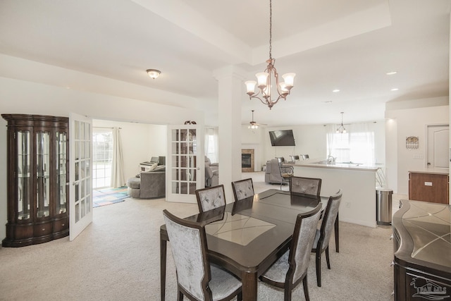 dining area featuring recessed lighting, a notable chandelier, light colored carpet, and a glass covered fireplace