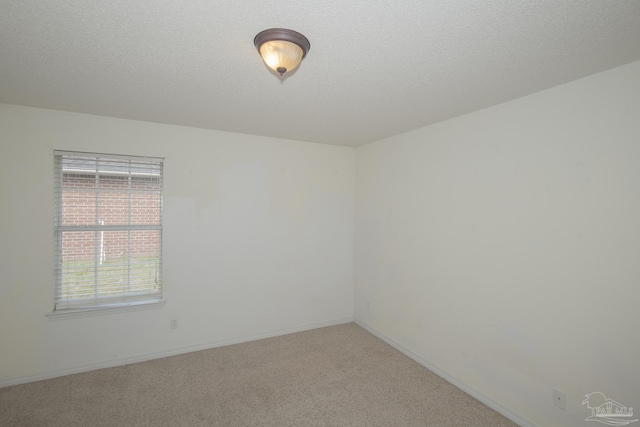 unfurnished room featuring a textured ceiling, baseboards, and light colored carpet