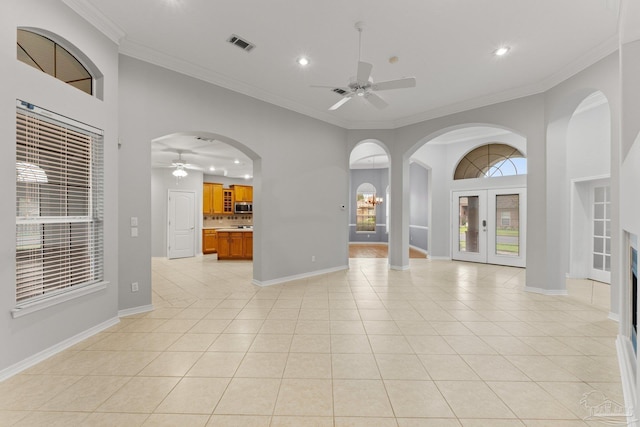 spare room with a high ceiling, ceiling fan, light tile patterned floors, and crown molding