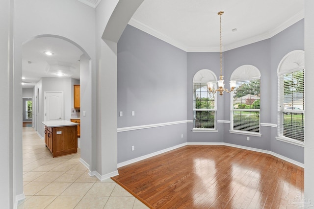 unfurnished room with light wood-type flooring, crown molding, and a chandelier