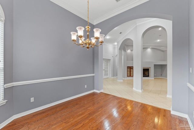 unfurnished dining area with built in shelves, ornamental molding, light hardwood / wood-style flooring, and a notable chandelier