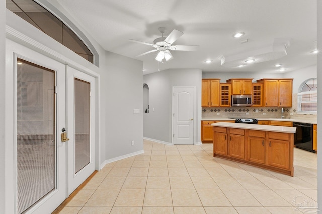 kitchen with ceiling fan, light tile patterned floors, a kitchen island, backsplash, and black appliances