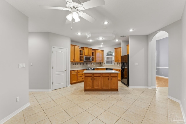 kitchen featuring backsplash, black fridge with ice dispenser, light tile patterned floors, a center island, and ceiling fan