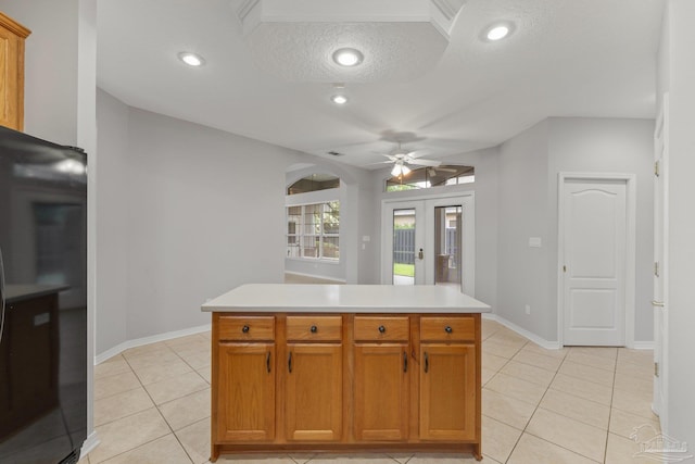 kitchen with black refrigerator, a center island, ceiling fan, and a textured ceiling