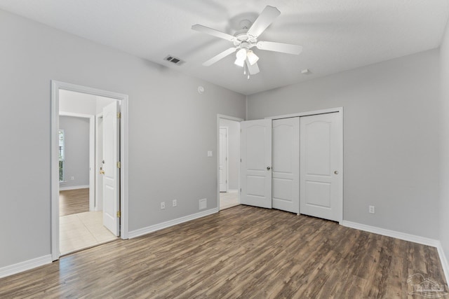 unfurnished bedroom with a closet, a textured ceiling, dark wood-type flooring, ensuite bath, and ceiling fan