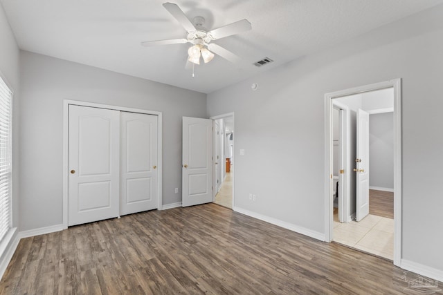 unfurnished bedroom with wood-type flooring, a textured ceiling, a closet, and ceiling fan