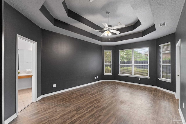 unfurnished room featuring ceiling fan, hardwood / wood-style flooring, a raised ceiling, and a textured ceiling