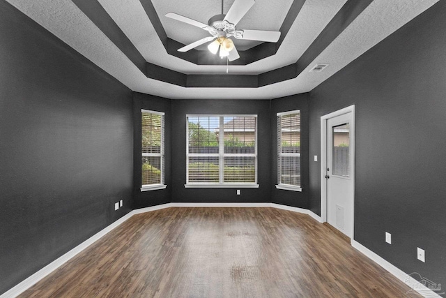 unfurnished room with ceiling fan, a raised ceiling, and dark hardwood / wood-style flooring