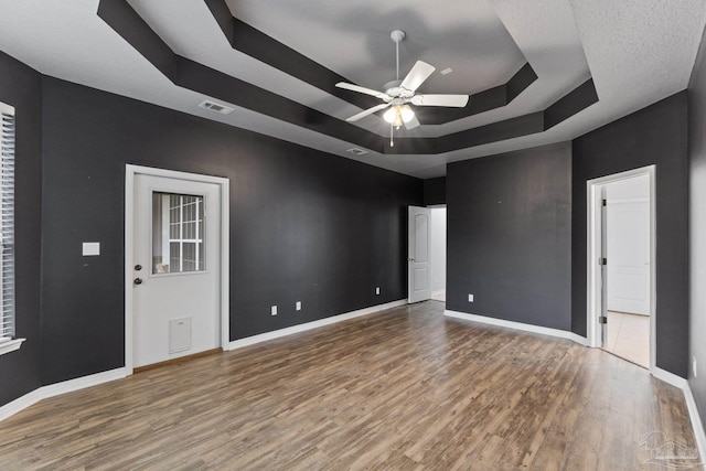 unfurnished room featuring a raised ceiling, ceiling fan, and hardwood / wood-style flooring