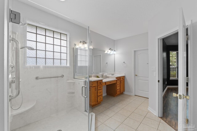 bathroom with a healthy amount of sunlight, tile patterned flooring, a shower with door, and vanity