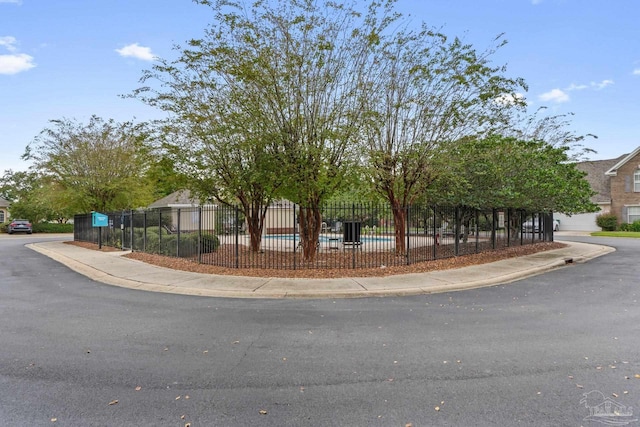 view of property hidden behind natural elements featuring a fenced in pool