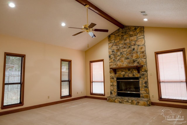 unfurnished living room with a stone fireplace, beam ceiling, ceiling fan, light carpet, and a textured ceiling