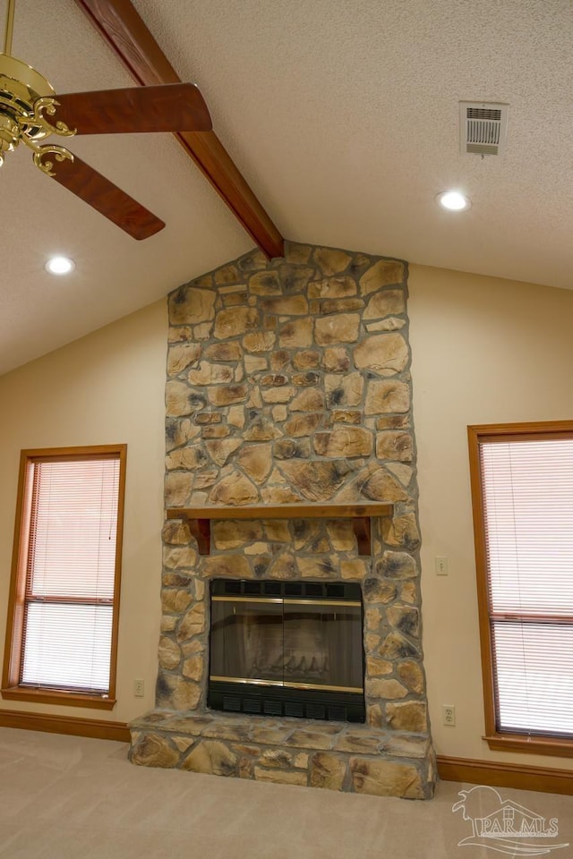 room details with a stone fireplace, carpet flooring, beam ceiling, ceiling fan, and a textured ceiling