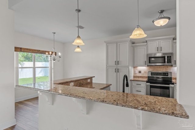 2006 Costa Verde Ct, Navarre, FL 32566 - kitchen featuring appliances with stainless steel finishes, tasteful backsplash, a kitchen bar, baseboards, and light stone countertops