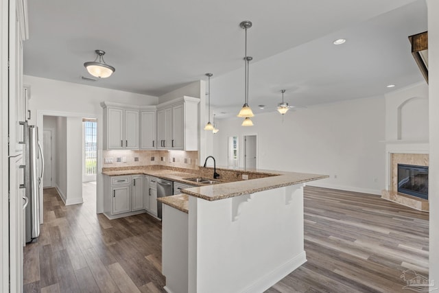 2006 Costa Verde Ct, Navarre, FL 32566 - kitchen featuring a sink, a ceiling fan, open floor plan, light stone counters, and a peninsula