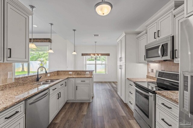 2006 Costa Verde Ct, Navarre, FL 32566 - kitchen featuring appliances with stainless steel finishes, a sink, dark wood-type flooring, a peninsula, and backsplash