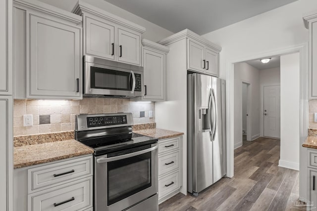 2006 Costa Verde Ct, Navarre, FL 32566 - kitchen featuring appliances with stainless steel finishes, decorative backsplash, wood finished floors, light stone counters, and baseboards