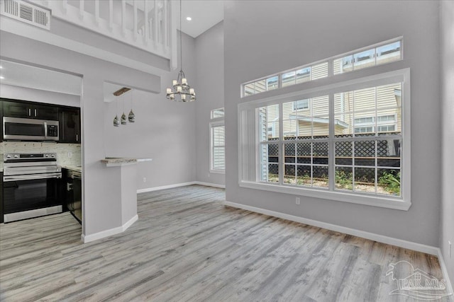 601 E Burgess Rd Unit J2, Pensacola, FL 32504 - kitchen with stainless steel appliances, a chandelier, light wood-type flooring, dark cabinets, and a high ceiling