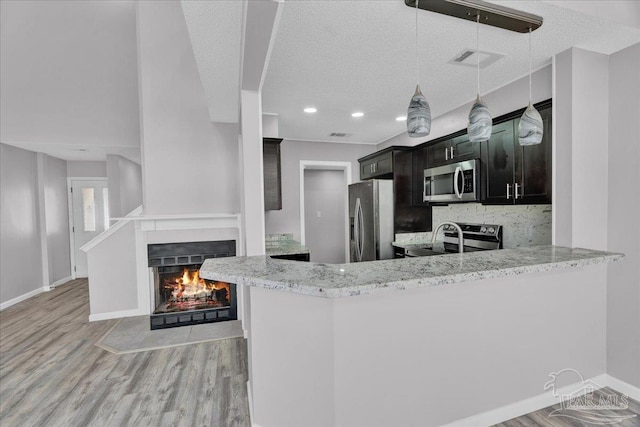 601 E Burgess Rd Unit J2, Pensacola, FL 32504 - kitchen with stainless steel appliances, light wood finished floors, a warm lit fireplace, light stone countertops, and baseboards