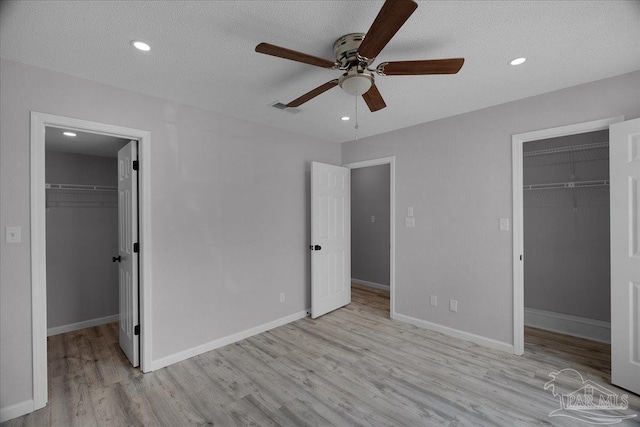 601 E Burgess Rd Unit J2, Pensacola, FL 32504 - unfurnished bedroom with a walk in closet, a closet, wood finished floors, a textured ceiling, and recessed lighting